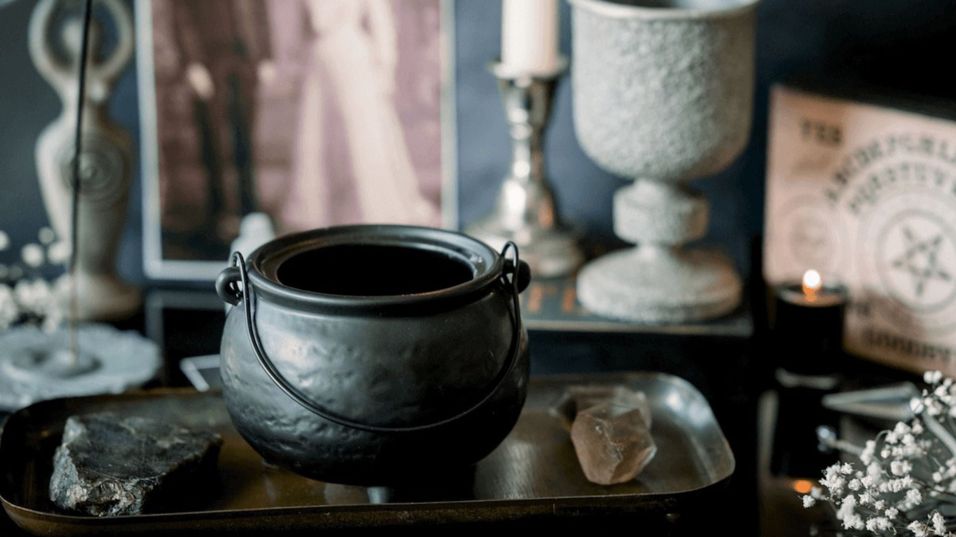 A collection of witchy accessories: a small cauldron, crystals, and candles