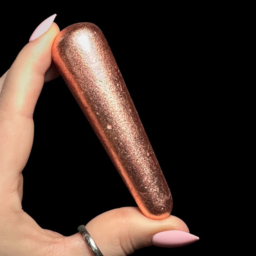 A person holding a shiny copper-colored object resembling a tapered cone.