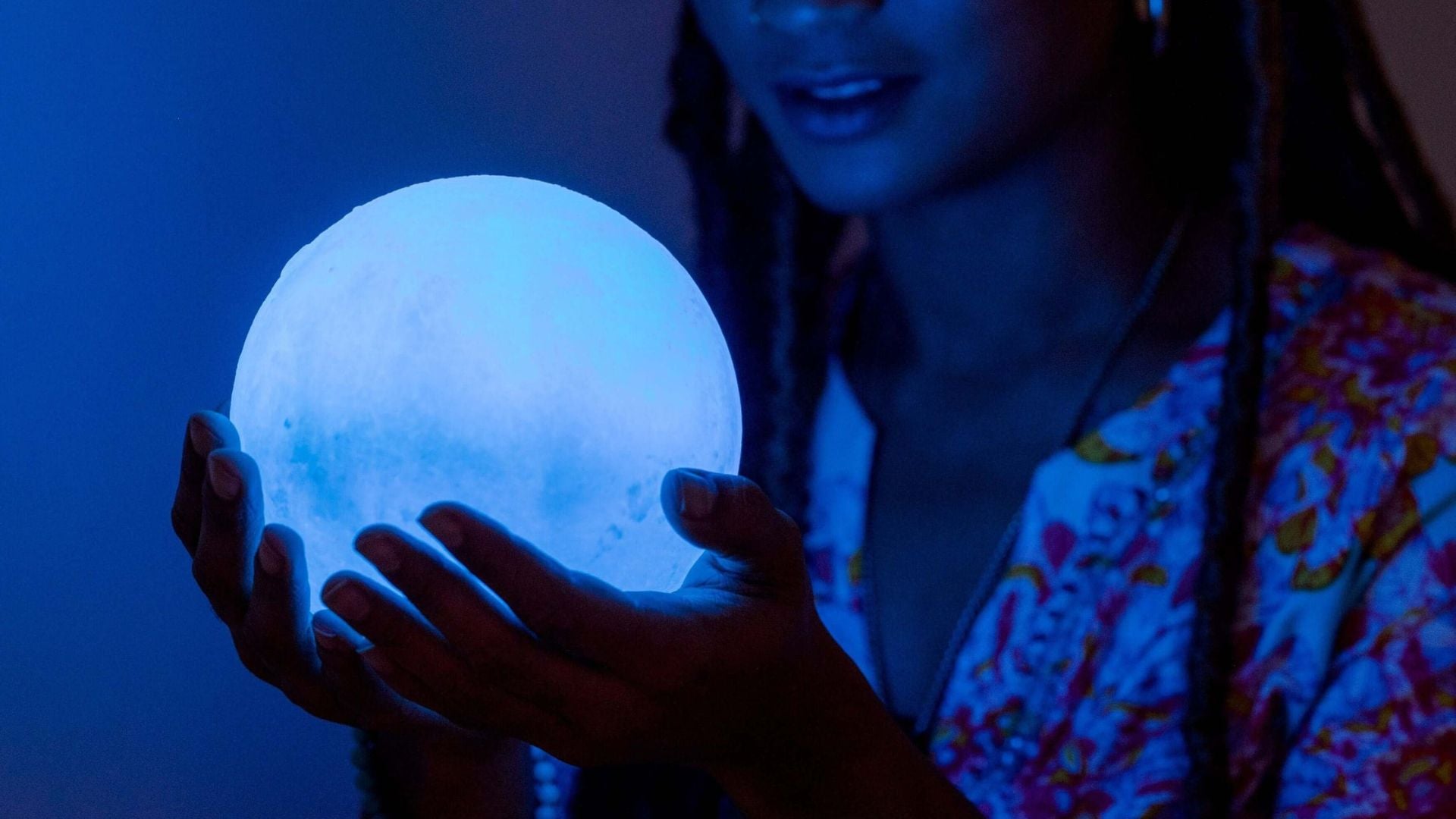 A woman holding a large selenite sphere that looks like the full moon