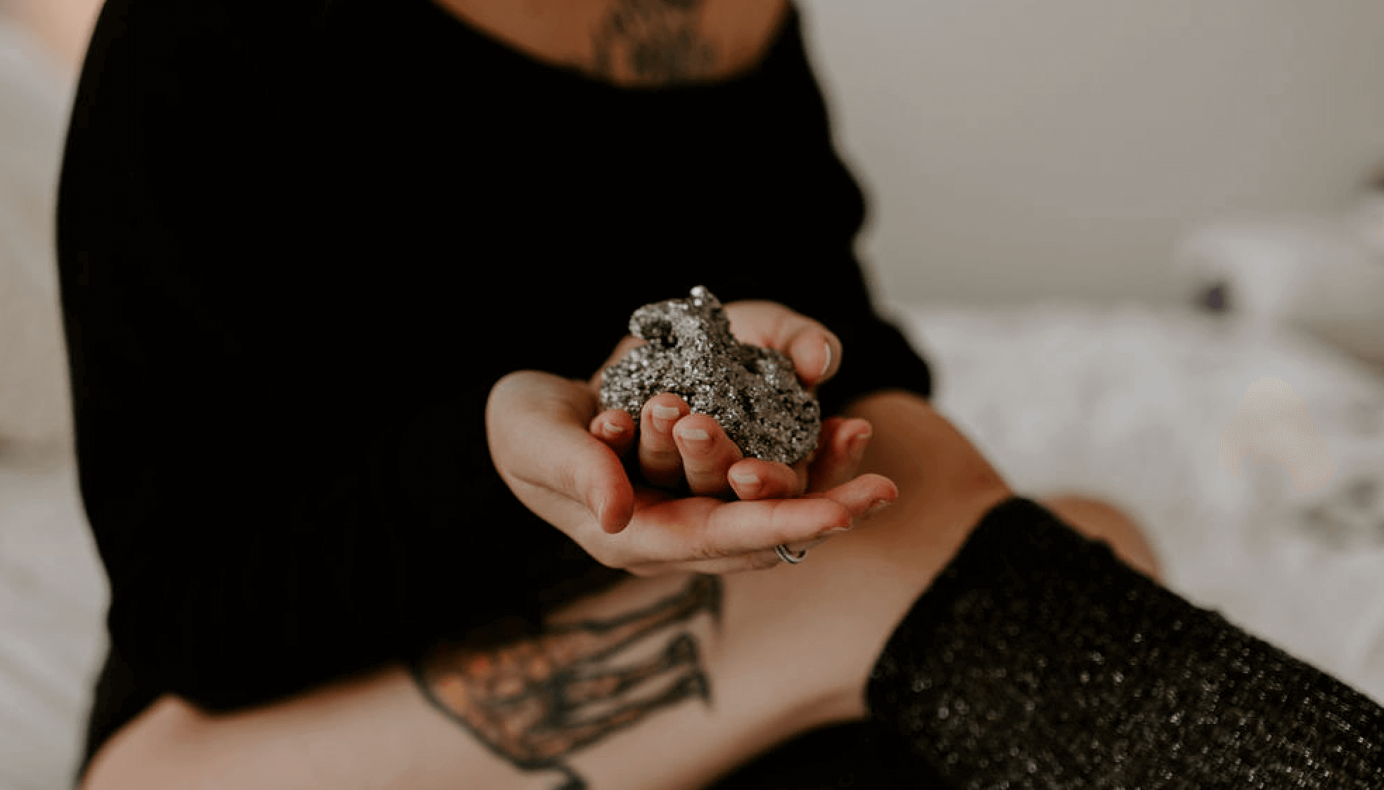 Woman wearing black sitting with a pyrite crystal in her hand