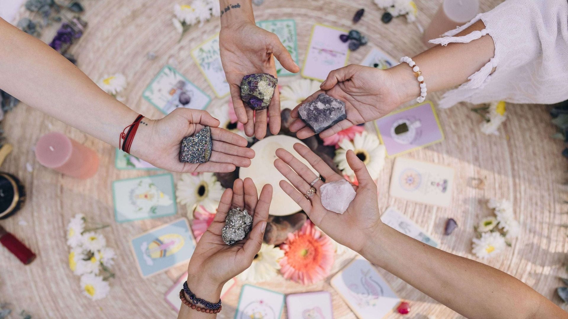women forming a circle with their outstretched hands holding crystals