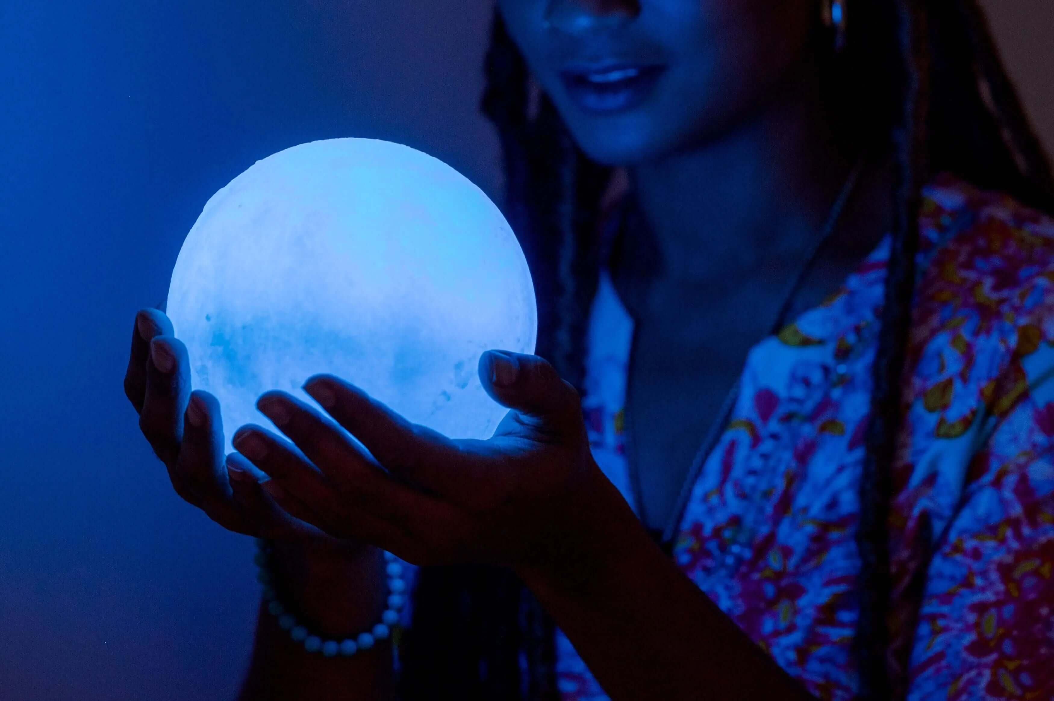 A woman holding a selenite sphere that looks like the full moon 